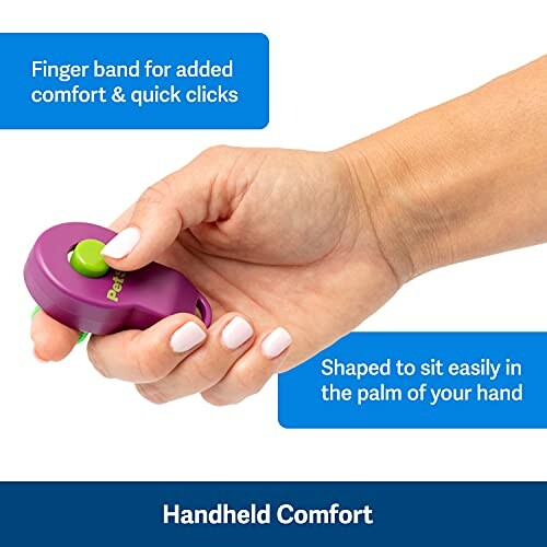 Hand holding a purple pet clicker with a green button, featuring a finger band for comfort.